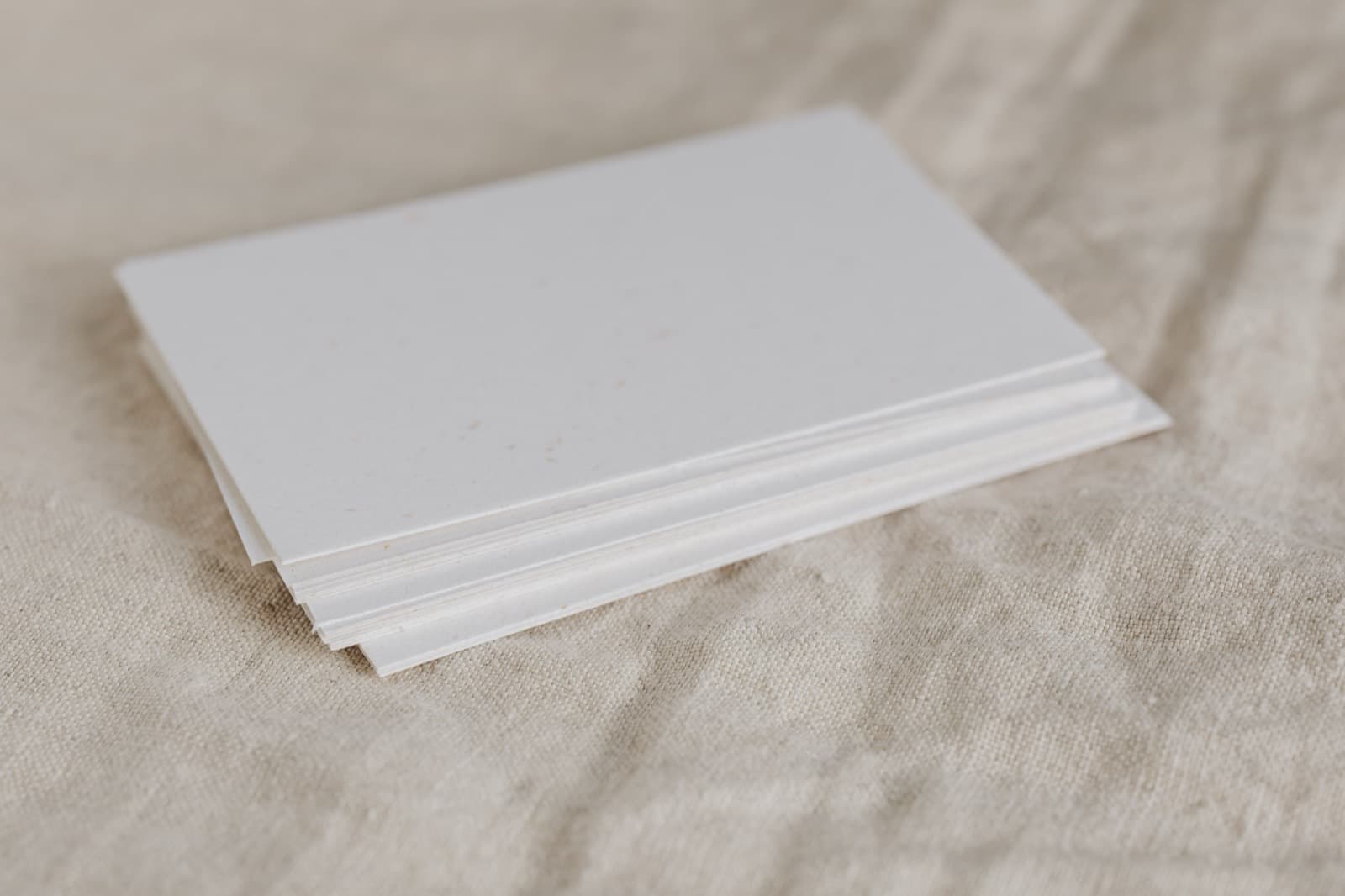 Pila de hojas de papel en blanco sobre una tela de lino clara